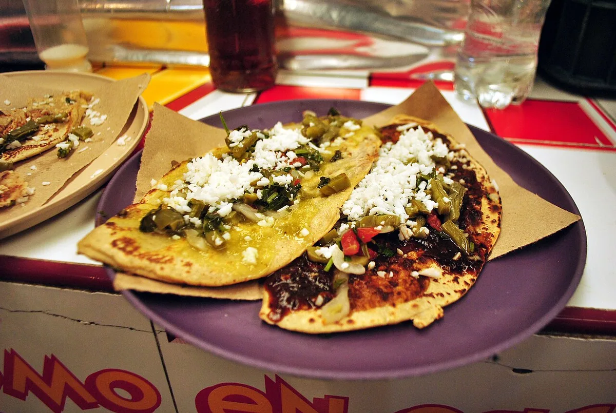 Tlacoyos topped with nopales, salsa, and crumbled cheese