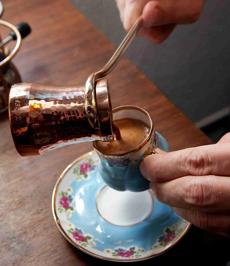 Turkish coffee poured from a copper cezve